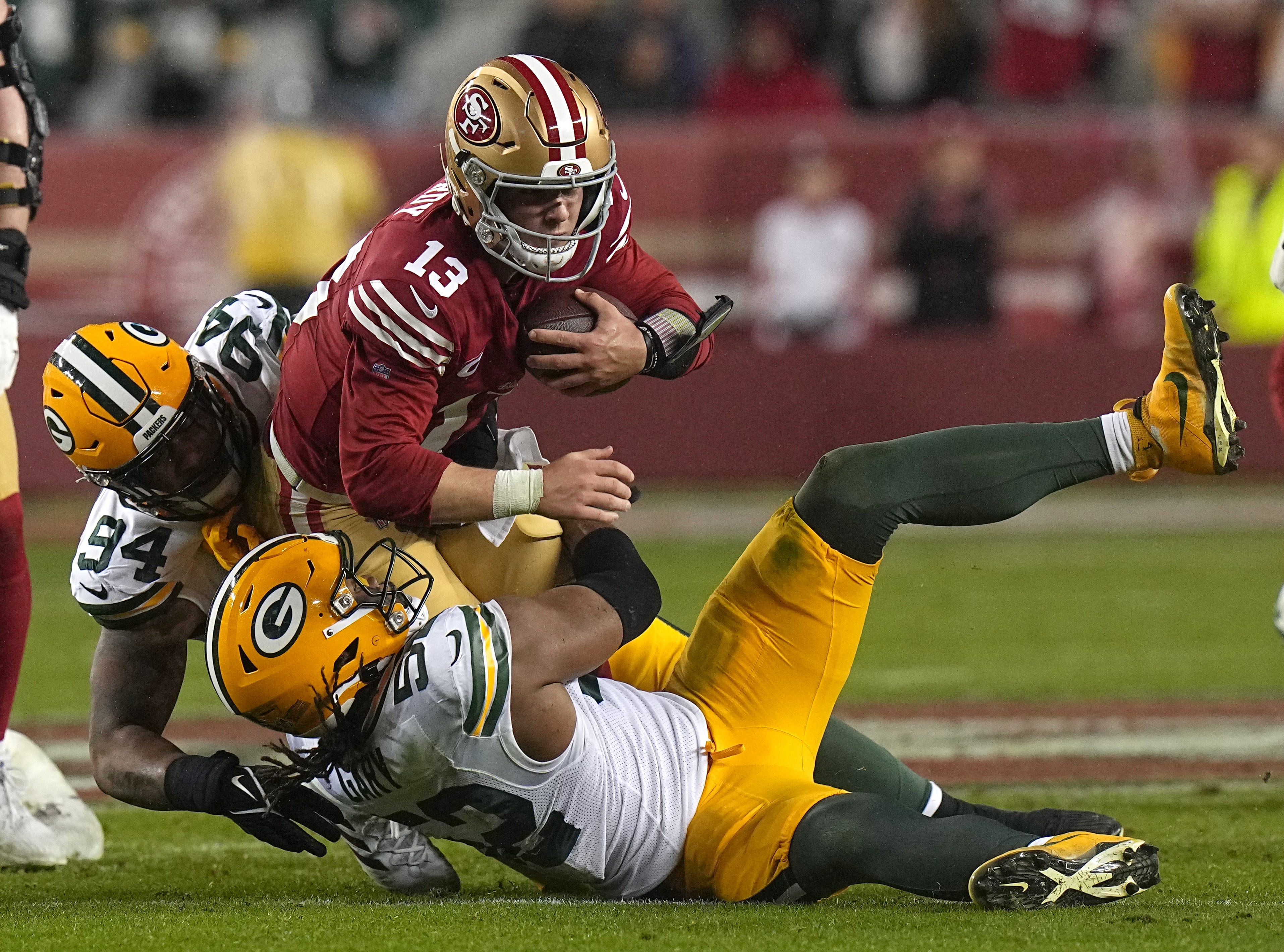 San Francisco 49ers quarterback Brock Purdy (13) is tackled by Green Bay Packers defensive end Karl Brooks (94) and Rashan Gary (52) after a one yard gain during the third quarter of their NFC divisional playoff game Saturday, January 20, 2024 at Levi’ Stadium in Santa Clara, California. The San Francisco 49ers beat the Green Bay Packers 24-21.