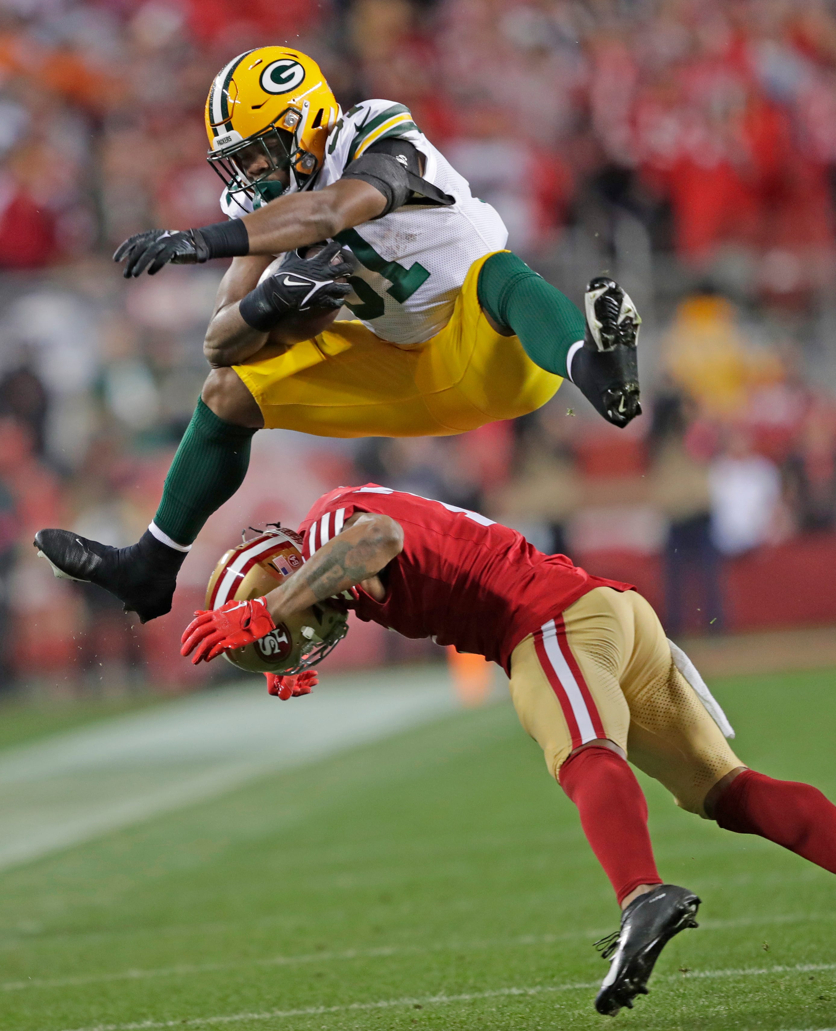 Green Bay Packers running back Emanuel Wilson (31) hurdles San Francisco 49ers linebacker Dre Greenlaw (57) in the fourth quarter during their NFC divisional playoff football game Saturday, January 20, 2024, at Levi's Stadium in Santa Clara, California.