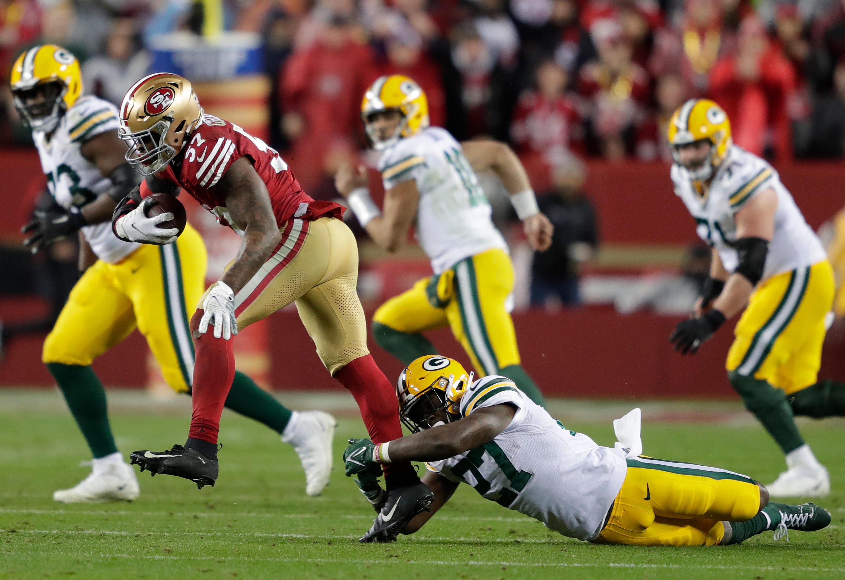 San Francisco 49ers linebacker Dre Greenlaw (57) eludes Green Bay Packers cornerback Zyon Gilbert (27) after intercepting a pass in the third quarter during their NFC divisional playoff football game Saturday, January 20, 2024, at Levi's Stadium in Santa Clara, California.