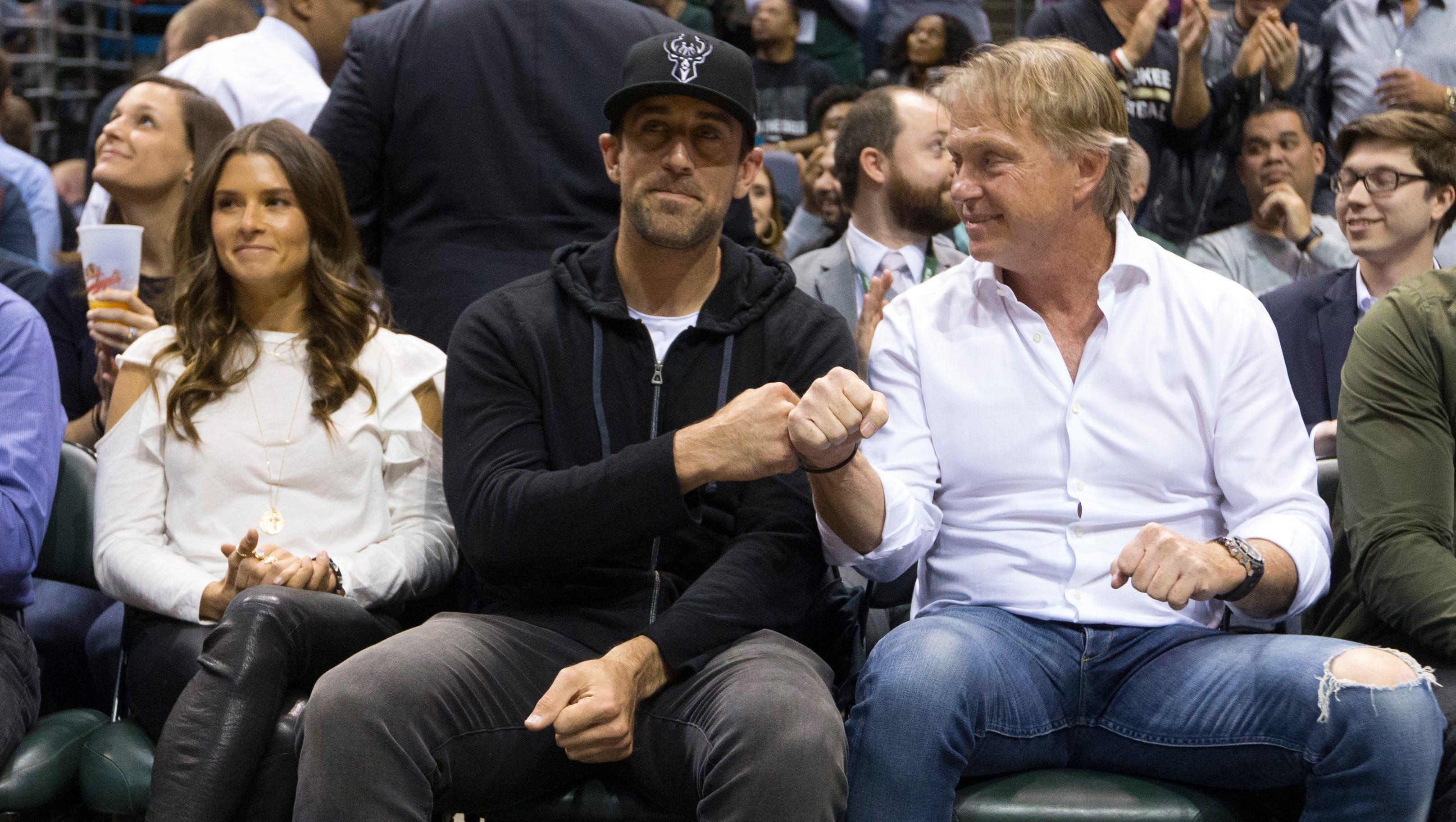 Green Bay Packers quarterback Aaron Rodgers (left) fist bumps Wes Edens, an owner of the Milwaukee Bucks, after it was announced Rodgers had joined the Bucks' ownership team. Next to Rodgers is race car driver Danica Patrick.
