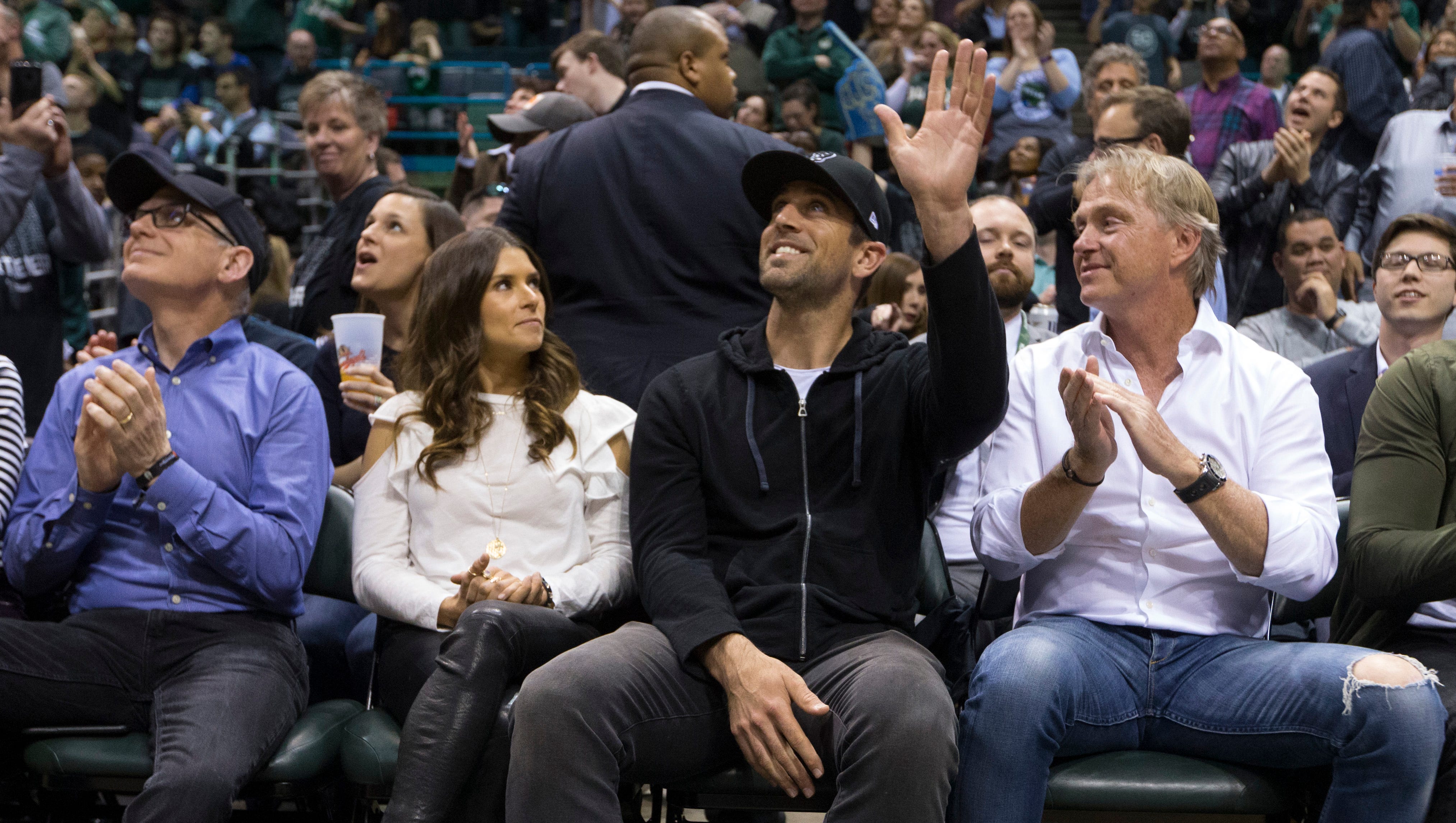 Green Bay Packers quarterback Aaron Rodgers waves to the crowd  at the BMO Harris Bradley Center while sitting next to Milwaukee Bucks owner Wes Edens after it was announced Rodgers joined the local ownership team of the Bucks during a Game 3 playoff against the Boston Celtics in Milwaukee. Next to Rodgers is race car driver Danica Patrick.