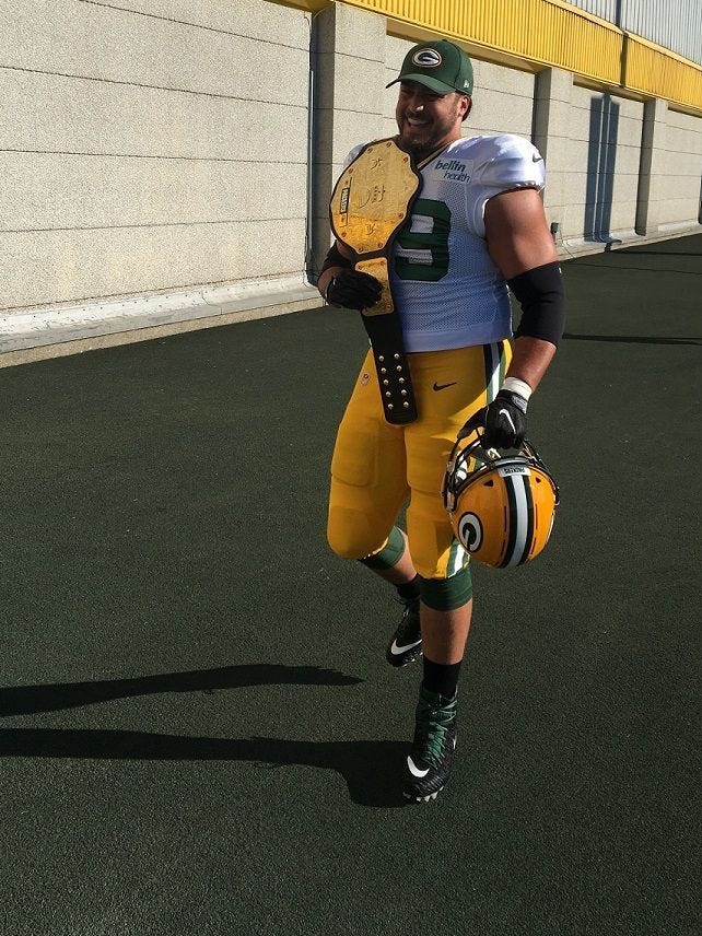 Green Bay Packers left tackle David Bakhtiari brings a WWE-style heavyweight belt onto the practice field during training camp in 2017.