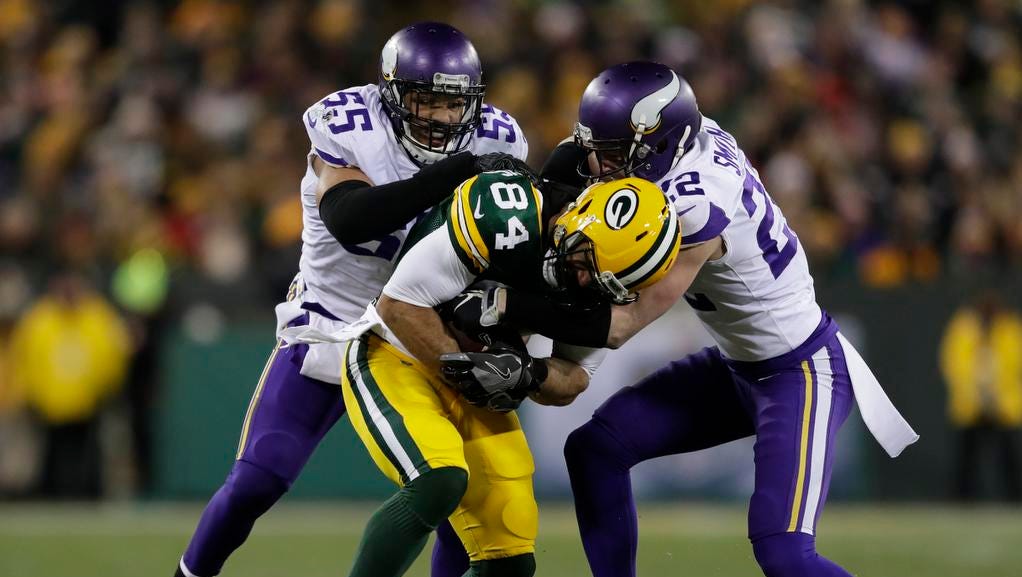 Green Bay Packers tight end Lance Kendricks (84) is brought down by Minnesota Vikings outside linebacker Anthony Barr (55) and free safety Harrison Smith (22) in the second quarter Saturday, December 23, 2017, at Lambeau Field in Green Bay, Wis.