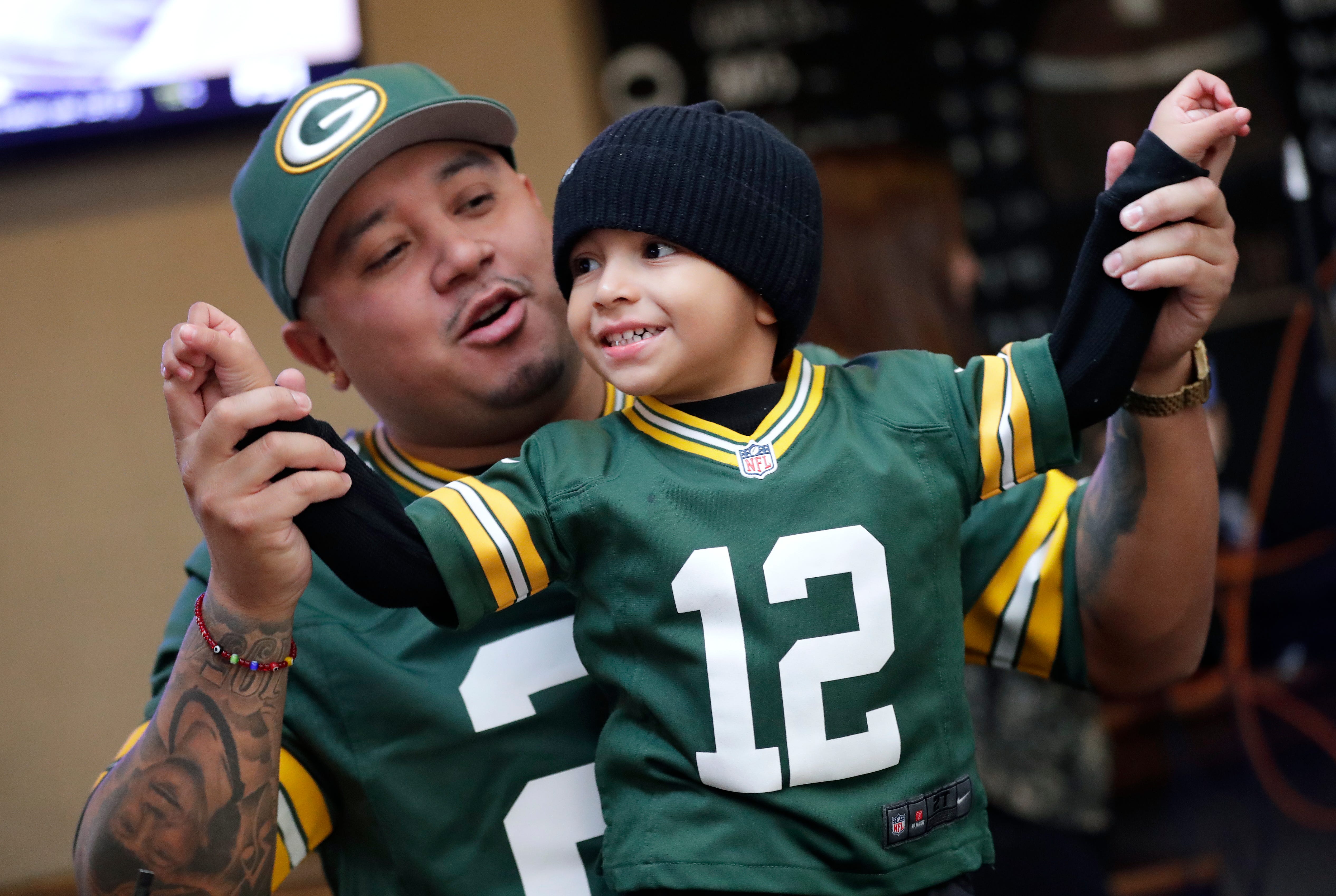 Green Bay Packers fan William Guifarro of Richmond, California dances with his son Ellijah King Guifarro, 3, during the Packers Everywhere pep rally Friday, January 19, 2024, at The Patio in Palo Alto, California.