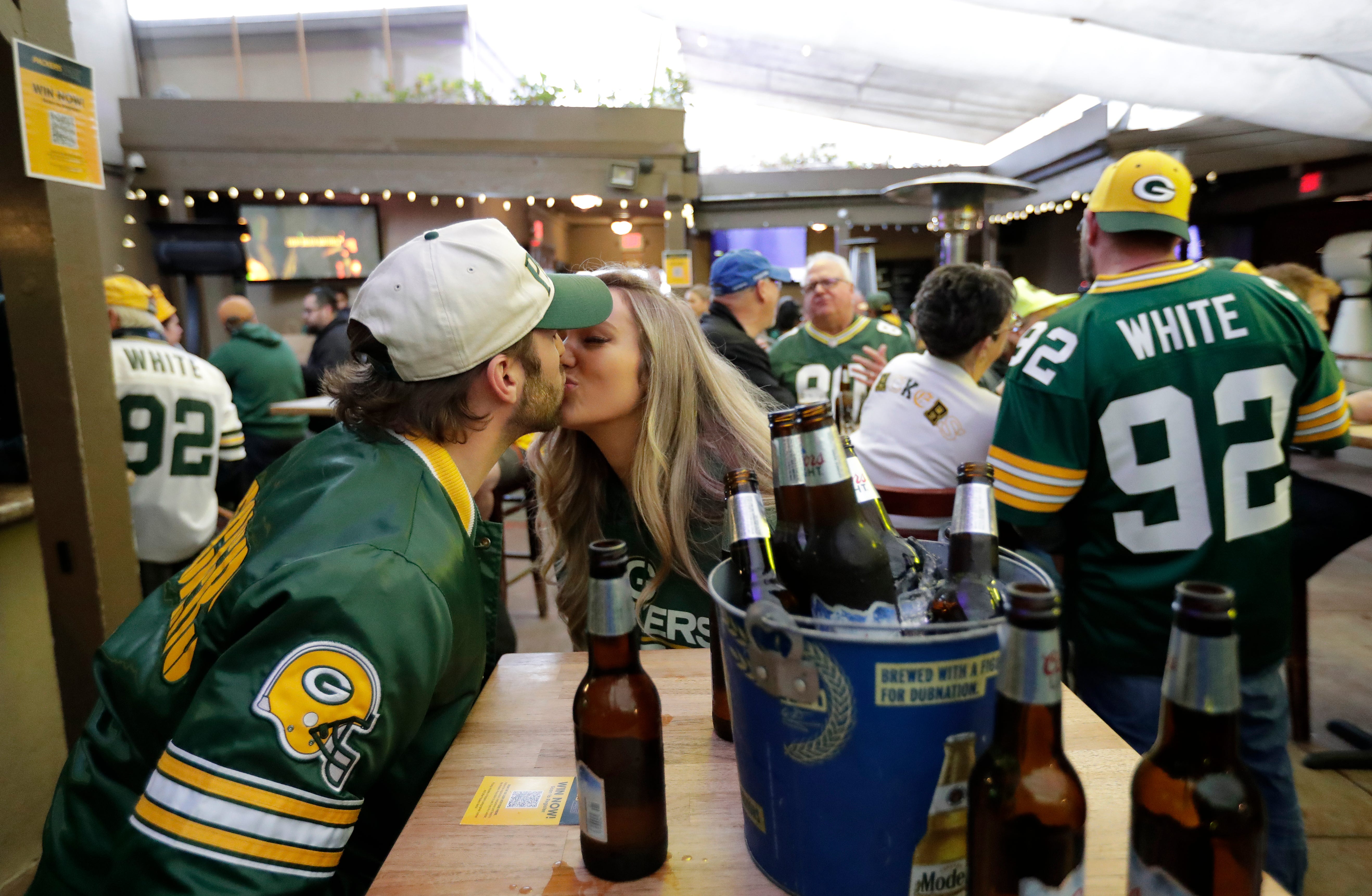 Green Bay Packers fans Tyler Hartzheim of Playa del Rey, California and his girlfriend Kimi McFarland of Hunington Beach, California sneak a kiss during the Packers Everywhere pep rally Friday, January 19, 2024, at The Patio in Palo Alto, California.