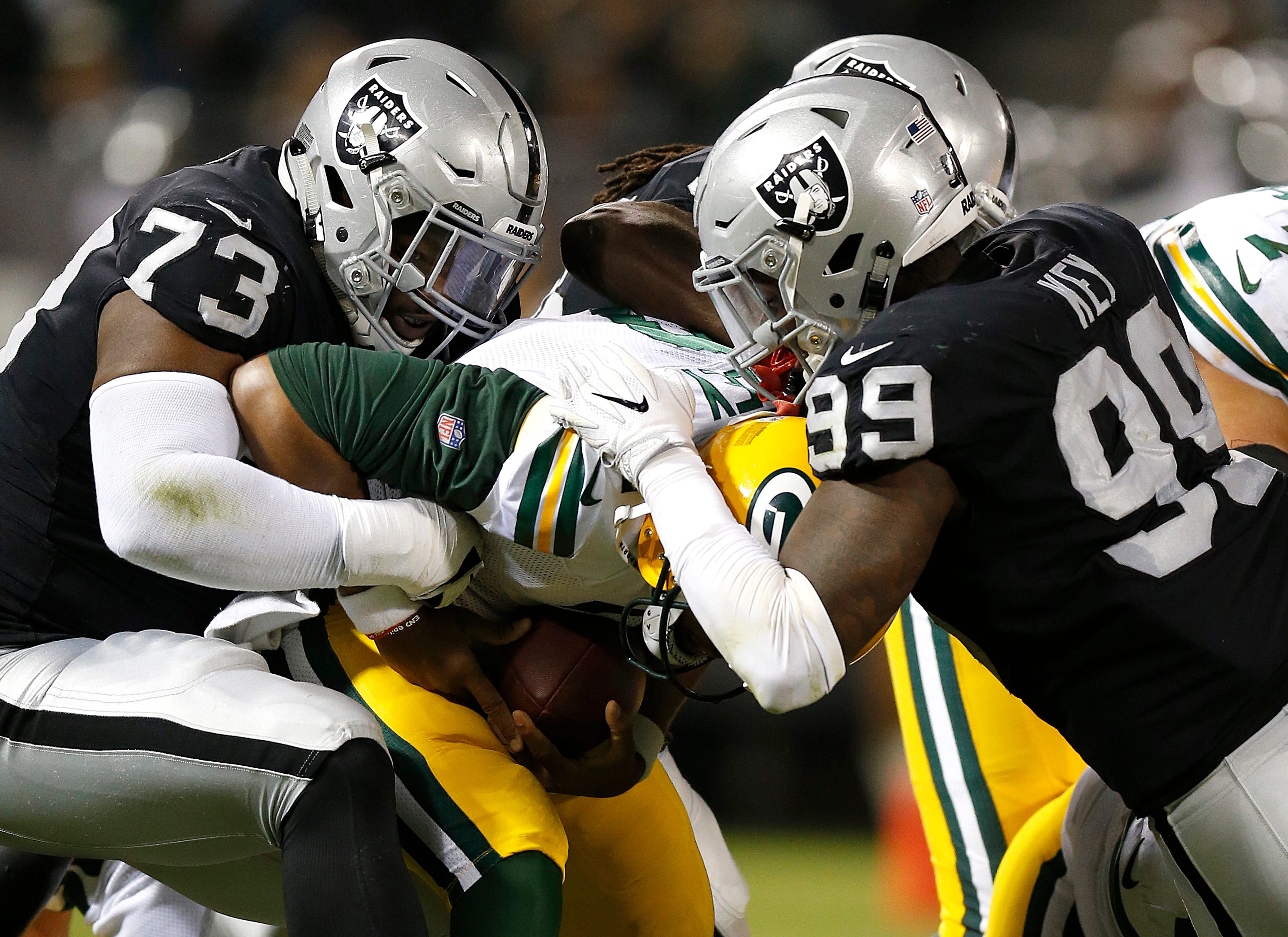 Green Bay Packers quarterback Brett Hundley, center, is sacked by Oakland Raiders defensive tackle Maurice Hurst (73) and defensive end Fadol Brown, obscured, during the first half of an NFL preseason football game in Oakland, Calif., Friday, Aug. 24, 2018. At right is Raiders defensive end Arden Key (99).