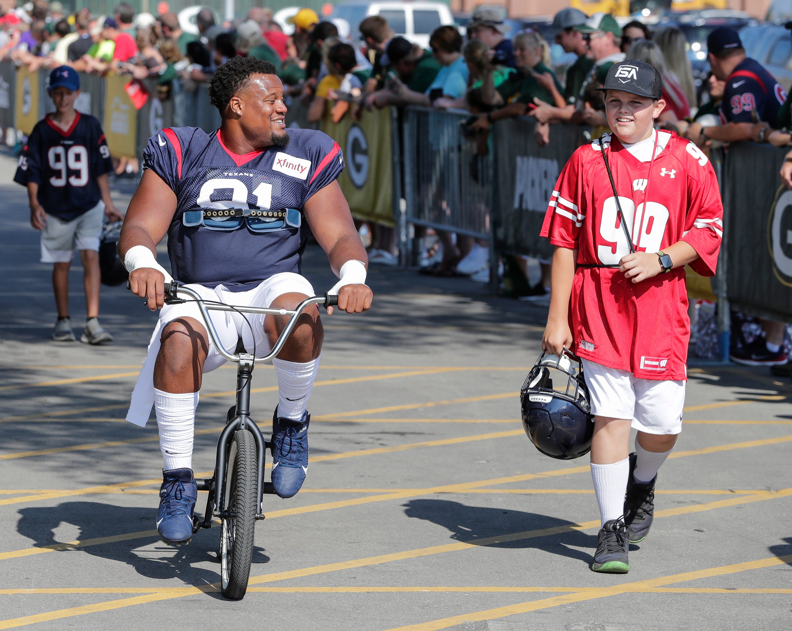 Texans defensive end Carlos Watkins (91) rides a bike to Clarke Hinkle Field for a joint training camp practice with the Green Bay Packers Monday, August 5, 2019, in Ashwaubenon, Wis.