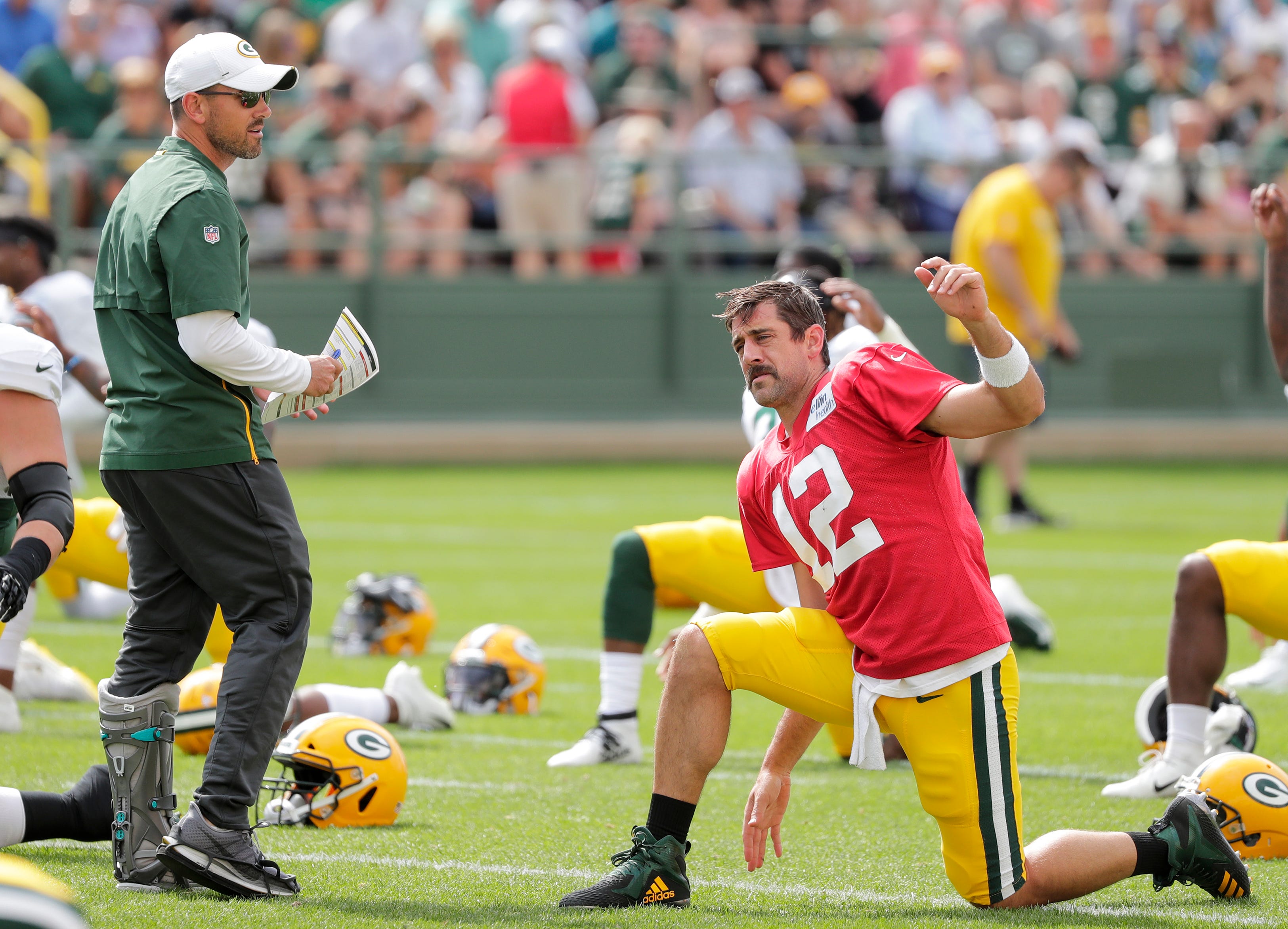 Green Bay Packers' head coach Matt LaFleur talks to Aaron Rodgers as he stretches during training camp practice Tuesday, August 13, 2019, at Ray Nitschke Field in Ashwaubenon, Wis.