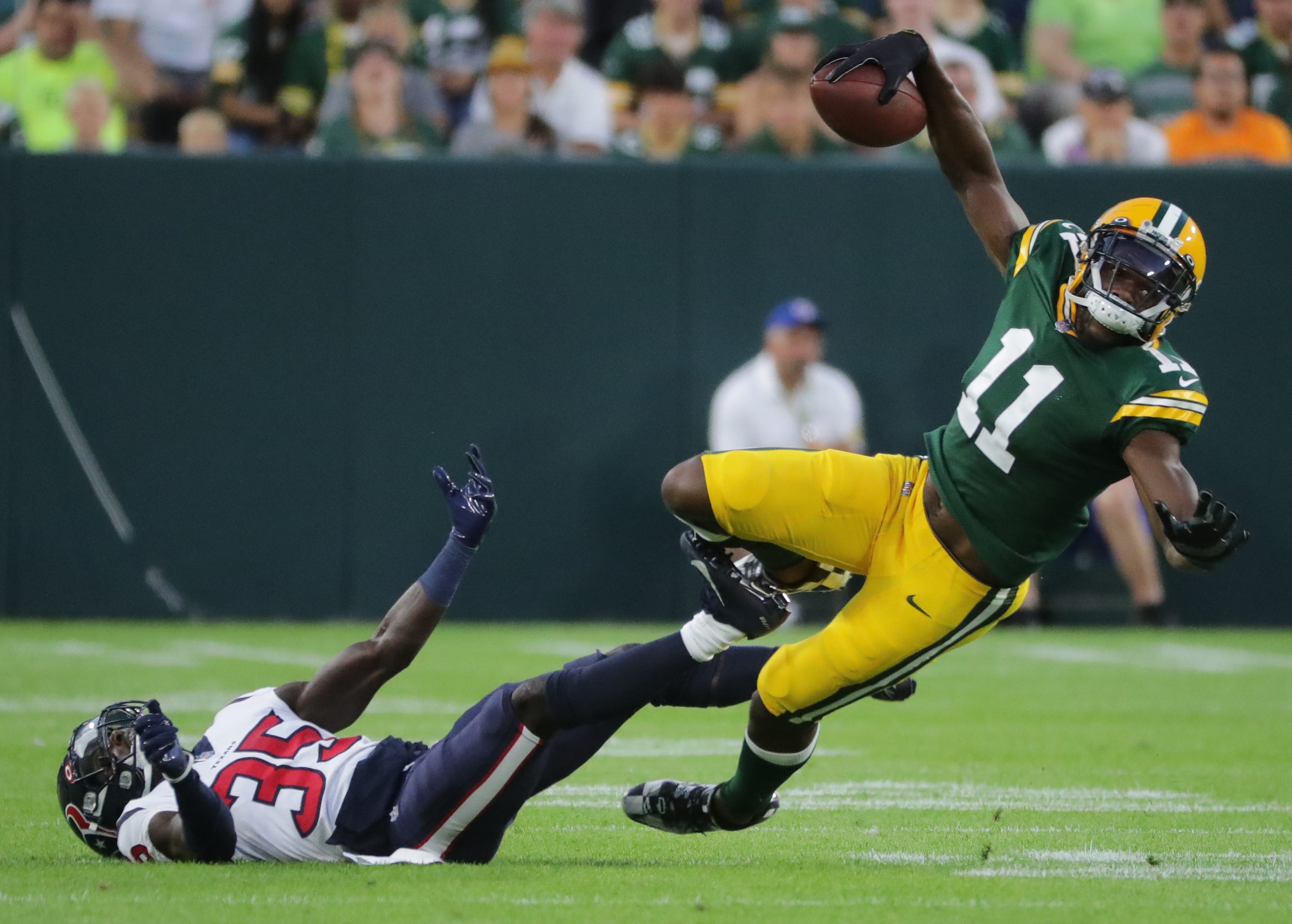 Green Bay Packers wide receiver Devin Funchess (11) is upended by Houston Texans defensive back Keion Crossen during their preseason game 21 at Lambeau Field in Green Bay.