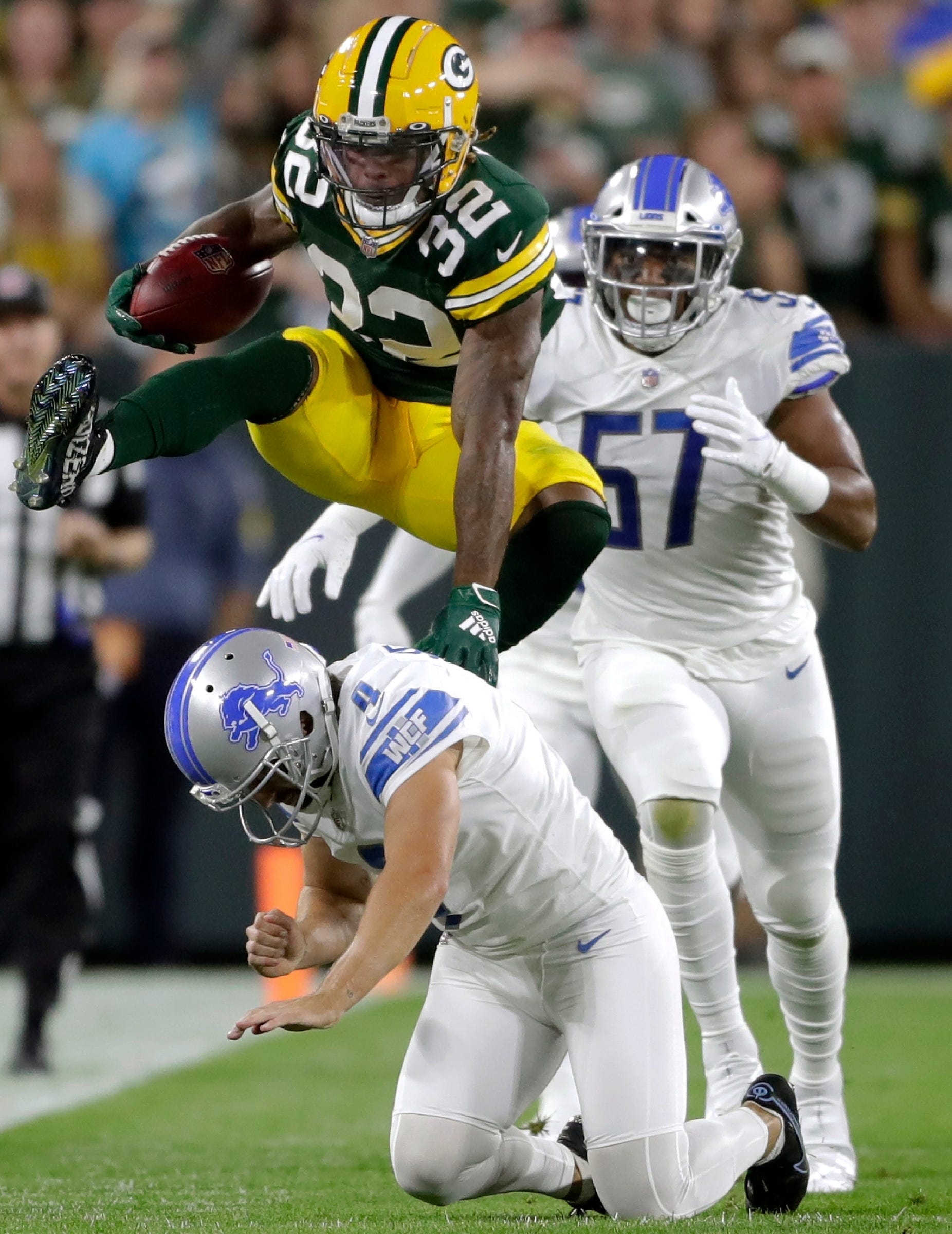 Green Bay Packers running back Kylin Hill (32) leaps a Detroit Lions defender at Lambeau Field on Monday, Sept. 20, 2021.