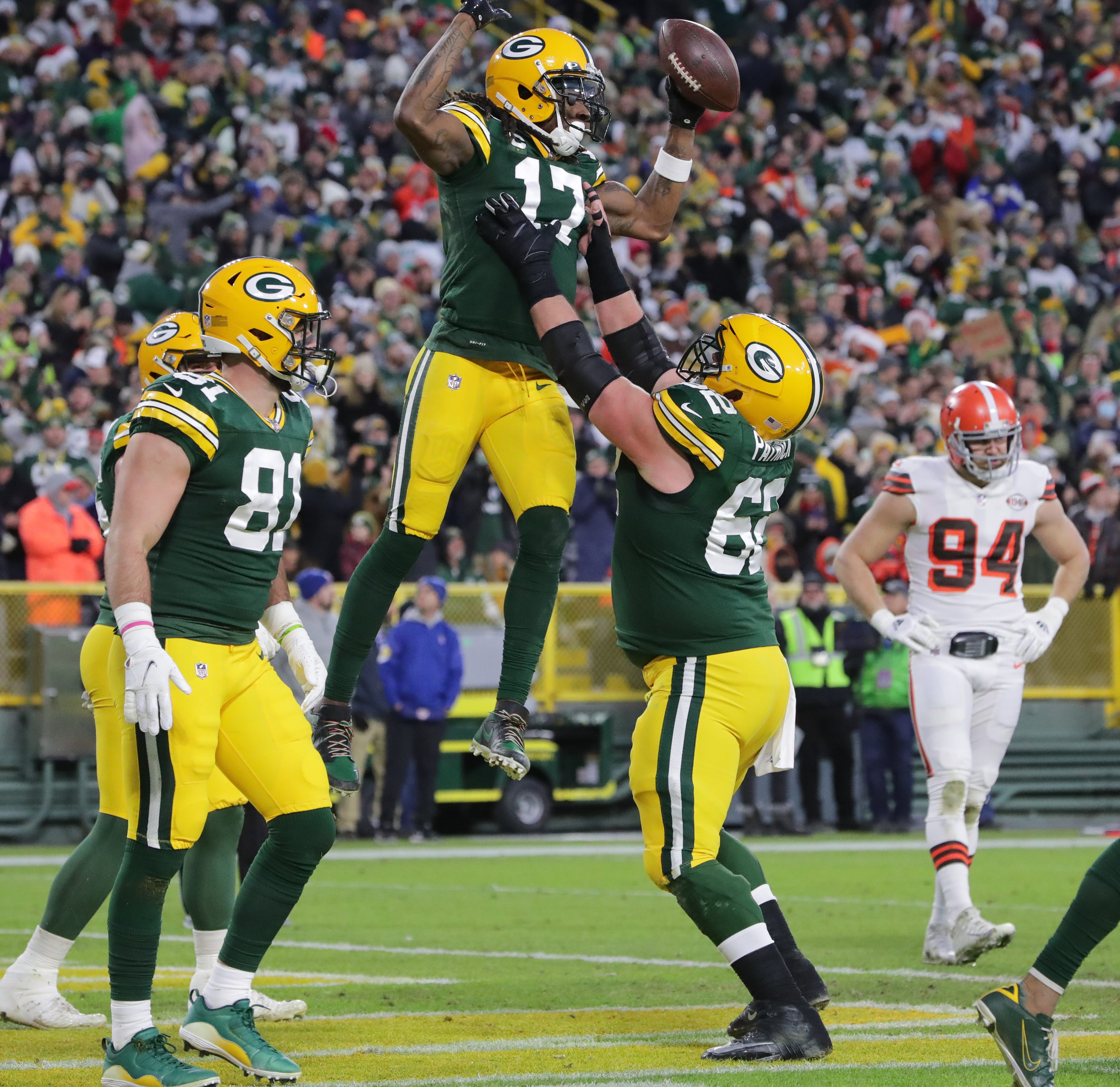 Green Bay Packers wide receiver Davante Adams (17) leaps into the arms of center Lucas Patrick (62) after catching a nine yard touchdown pass during the second  quarter of their game Saturday, December 25, 2021 at Lambeau Field in Green Bay, Wis.